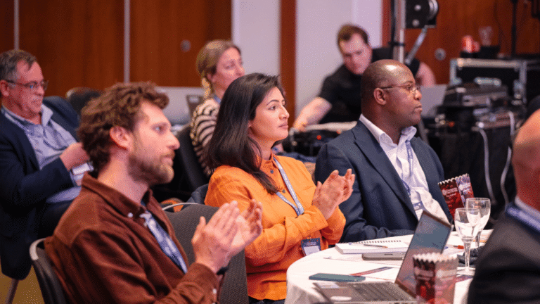 Conference attendees seated in an audience during an industry presentation